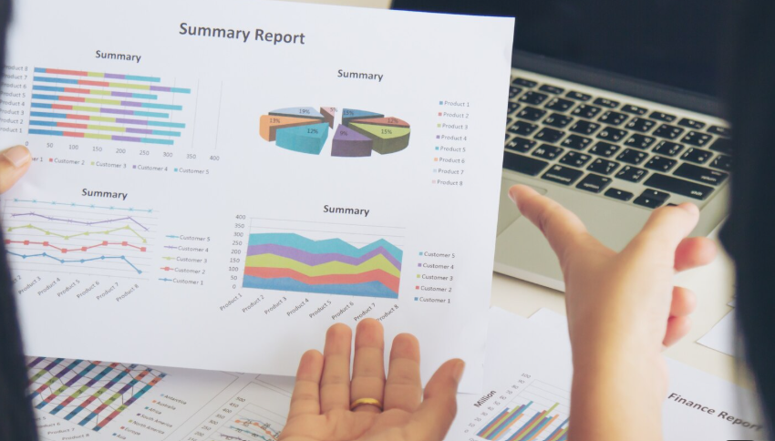 Printed summary report with charts beside a laptop