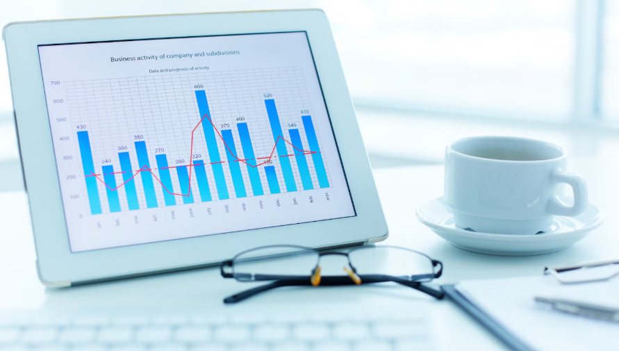 Tablet displaying a bar chart beside a notebook and coffee