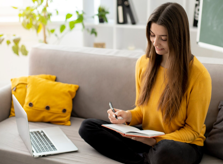 Researcher taking notes beside a laptop